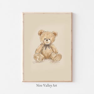 May include: A framed print with a watercolour illustration of a teddy bear. The bear is light brown with a dark brown bow tie, set against a light beige background. The text "Nire Valley Art" is at the bottom of the print.