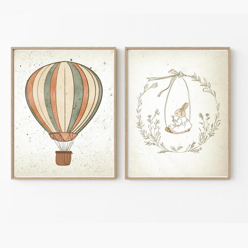 May include: Two framed prints, one with a hot air balloon with orange, green, and white stripes, and the other with a rabbit on a swing in a wreath of leaves.