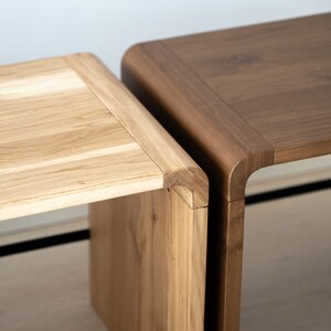 May include: Two wooden stools, one light brown and one dark brown, with rounded edges and a simple design.