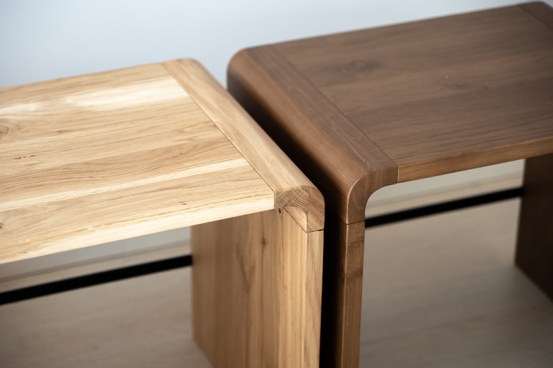May include: Two wooden stools, one light brown and one dark brown, with rounded edges and a simple design.