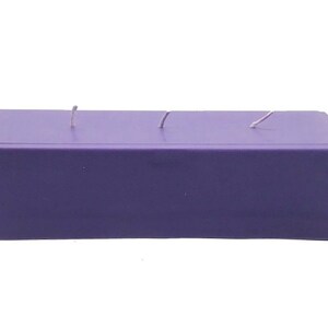 May include: A large, rectangular purple candle with three wicks.