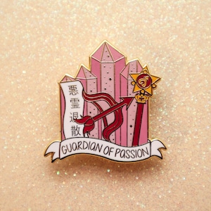 May include: Gold-tone enamel pin featuring a pink crystal design with a red and gold arrow and a scroll with the text "Guardian of Passion" and Chinese characters.
