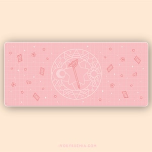 Puede incluir: Alfombrilla de ratón rosa y blanca con un patrón de cuadrícula y un contorno rosa de una varita mágica y un círculo con estrellas y símbolos. El texto "IVORYRUEMIA.COM" está en la parte inferior de la alfombrilla de ratón.