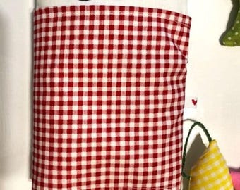 May include: A white cat-shaped plush toy with a red and white checkered blanket. The cat has a simple face with black eyes and a smiling mouth. A yellow fish-shaped toy with a checkered pattern hangs nearby.