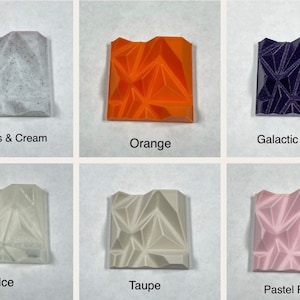 May include: Six small square tiles with different colours and textures. The tiles are arranged in two rows of three. The top row shows Cookies & Cream, Orange, and Galactic Purple. The bottom row shows Ice, Taupe, and Pastel Pink.