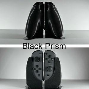 May include: A black, textured, 3D printed stand for a Nintendo Switch console. The stand is shaped like a prism and has a slot for the console to sit in. The text "Black Prism" is printed on the stand.