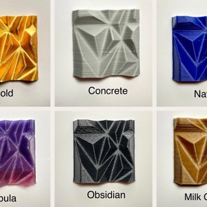 May include: Six small square tiles with a geometric pattern, each tile is a different colour: gold, concrete, navy, nebula, obsidian, and milk chocolate.