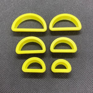 May include: Set of six yellow plastic cookie cutters shaped like half circles of varying sizes.