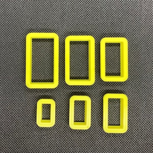 May include: Six yellow plastic cookie cutters in various rectangular shapes. The cutters are arranged in two rows of three.
