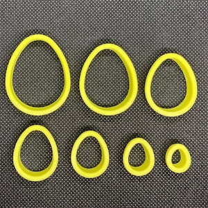 May include: Set of seven yellow plastic cookie cutters shaped like eggs, in various sizes.