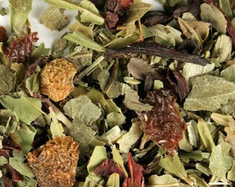 May include: Close-up of a blend of dried herbs and fruit pieces for herbal tea. The mix includes green leaves, red hibiscus flowers, and dried fruit pieces.