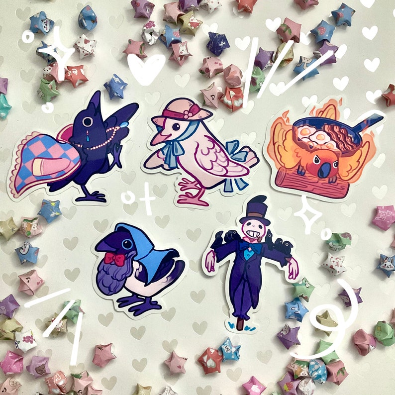 May include: A collection of whimsical stickers featuring cartoon birds and a koala. The stickers include a crow with a pearl necklace, a dove wearing a hat, and a koala cooking breakfast. Colorful origami stars surround the stickers.