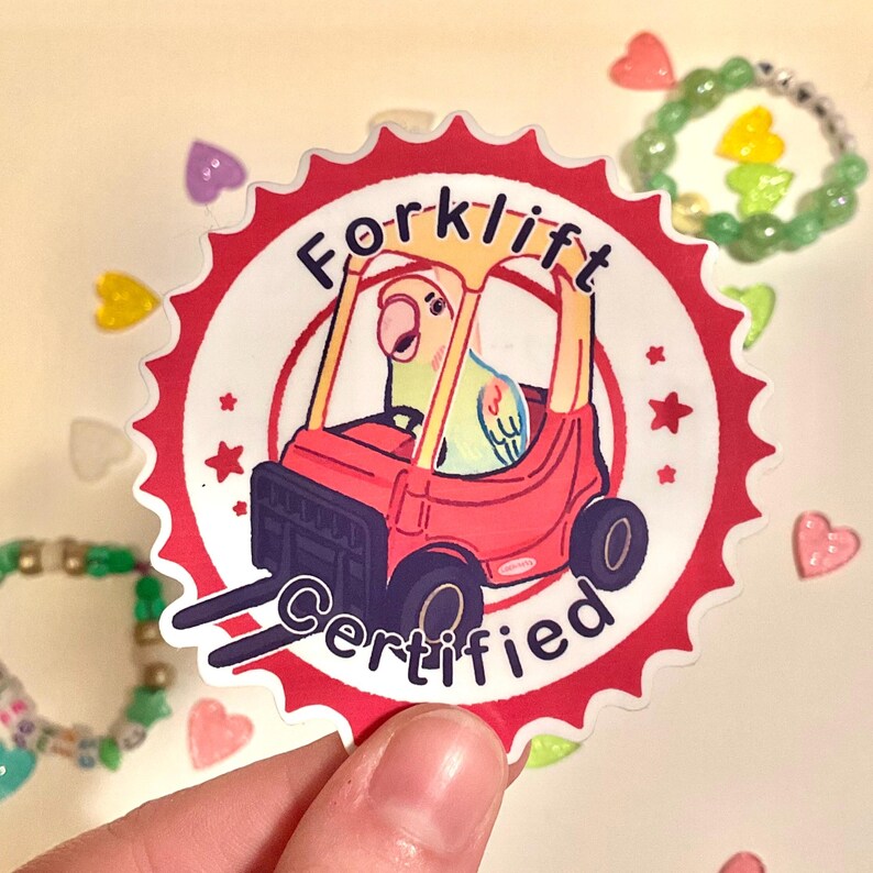 May include: A sticker featuring a cartoon parrot driving a red forklift. The sticker is circular with a red and white scalloped edge. Text on the sticker reads "Forklift Certified".