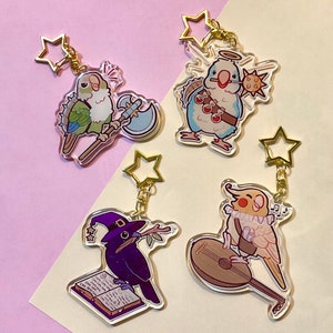 May include: Four acrylic keychains featuring cartoon birds in fantasy roles. One green bird holds an axe, another a mace and vials, a third a book and a witch hat, and the last plays a lute. Each keychain has a gold star clasp.