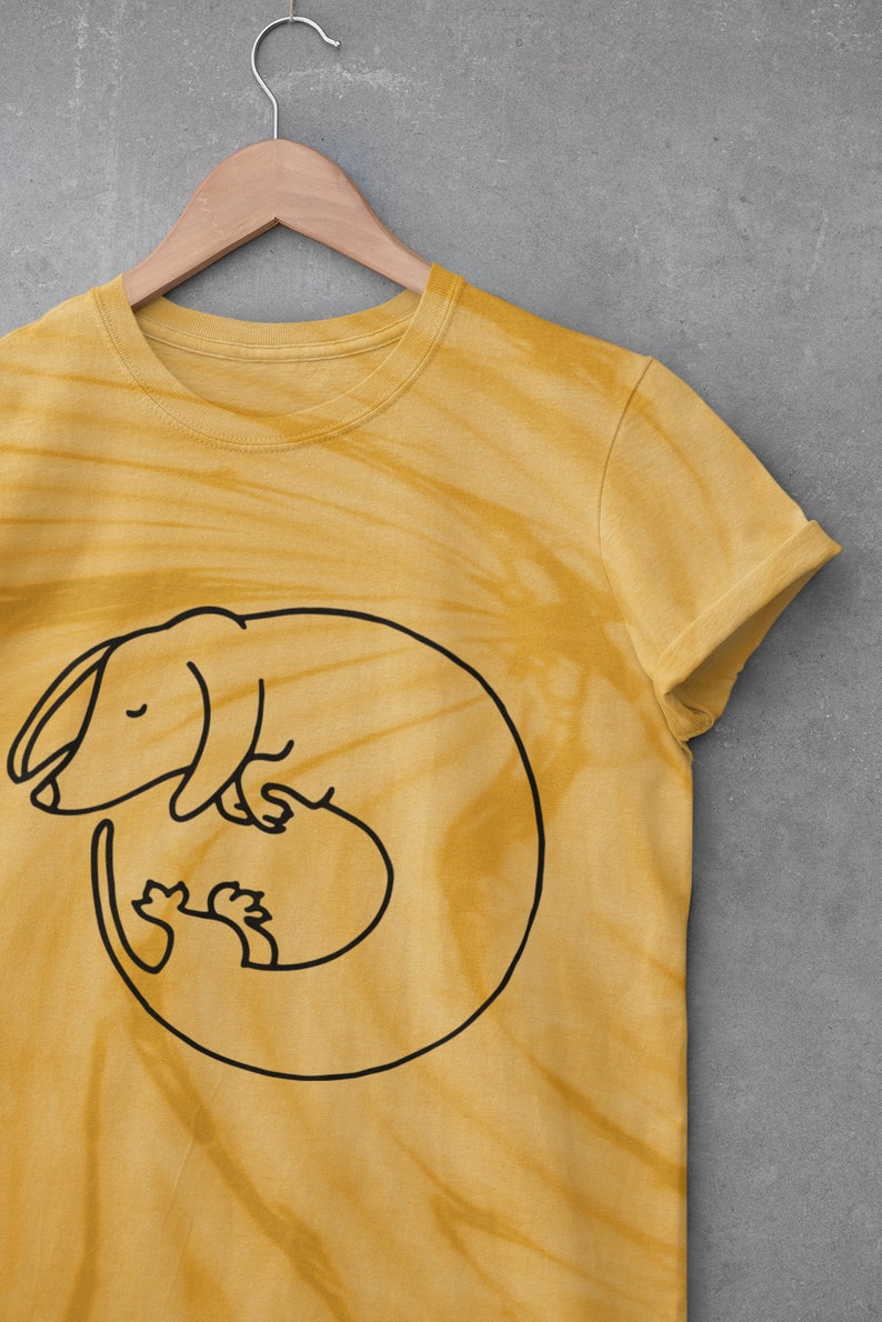 May include: A yellow tie-dye t-shirt with a black outline of a dachshund curled up sleeping.