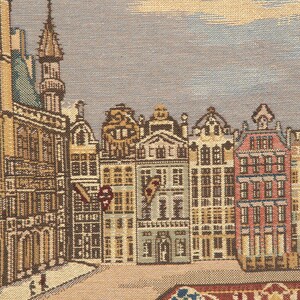 May include: A tapestry depicting a cityscape with a variety of buildings, including a tall tower, in a muted color palette of browns, tans, and blues. The buildings have intricate details and windows. The tapestry has a textured surface and a woven design.