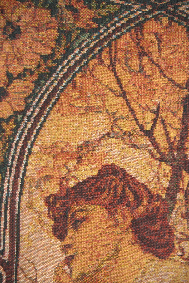 May include: Close-up of a tapestry featuring a woman's profile with auburn hair, set against a backdrop of warm orange and brown tones. The artwork includes floral and tree branch motifs, framed by a decorative border.