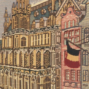 May include: A tapestry depicting a detailed view of a European city with tall buildings, intricate architecture, and a red flag hanging from a building.