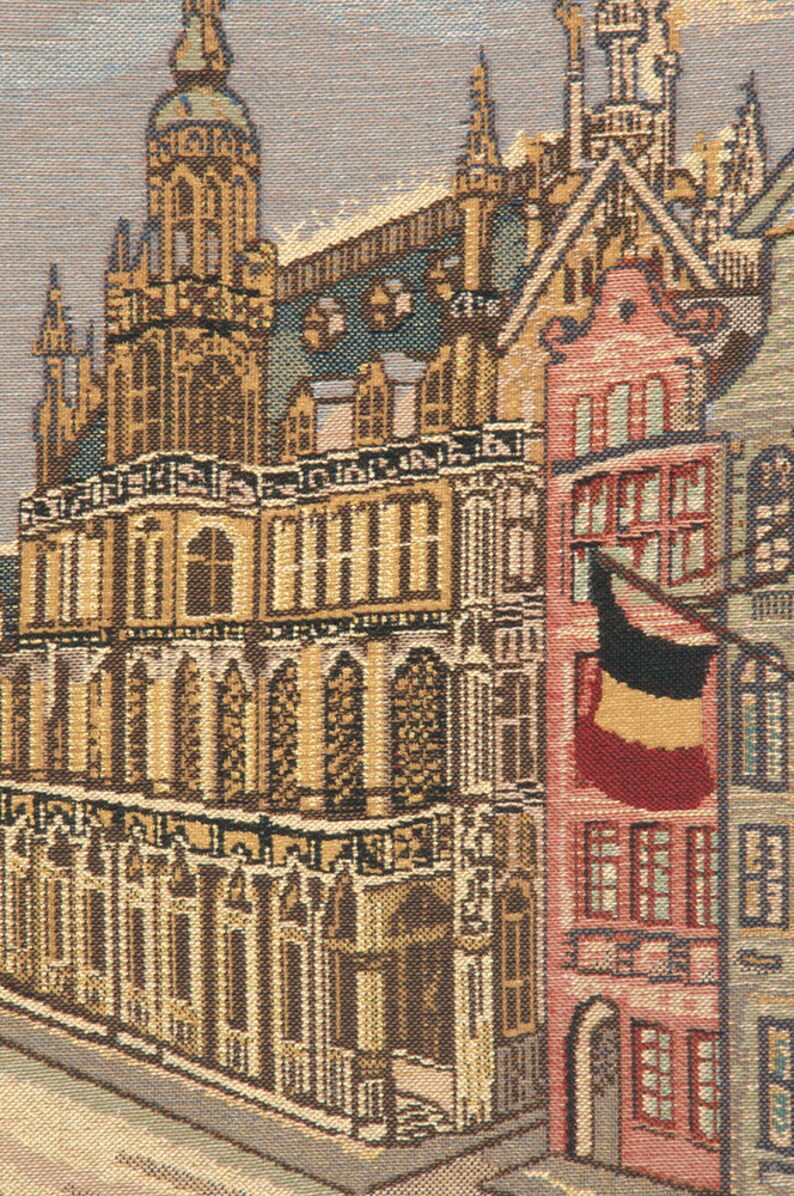May include: A tapestry depicting a detailed view of a European city with tall buildings, intricate architecture, and a red flag hanging from a building.