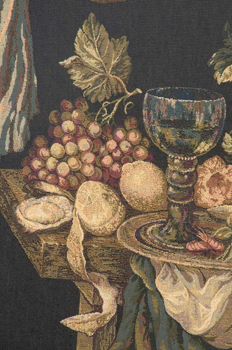 May include: A still life tapestry featuring a dark background with a wooden table, a glass of wine, grapes, lemons, and a white cloth.
