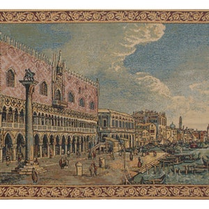 Peut inclure: Tapisserie tiss&eacute;e repr&eacute;sentant une ville d&eacute;taill&eacute;e avec un grand b&acirc;timent rose, une haute colonne et une sc&egrave;ne de bord de mer avec des bateaux. La tapisserie a une bordure d&eacute;corative et des glands.