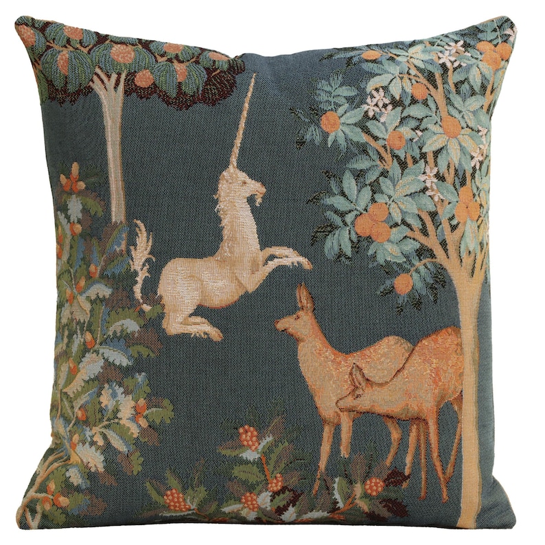 May include: A blue tapestry pillow featuring a white unicorn, two deer, and a green tree with orange fruit. The tapestry is woven with intricate details and a medieval style.