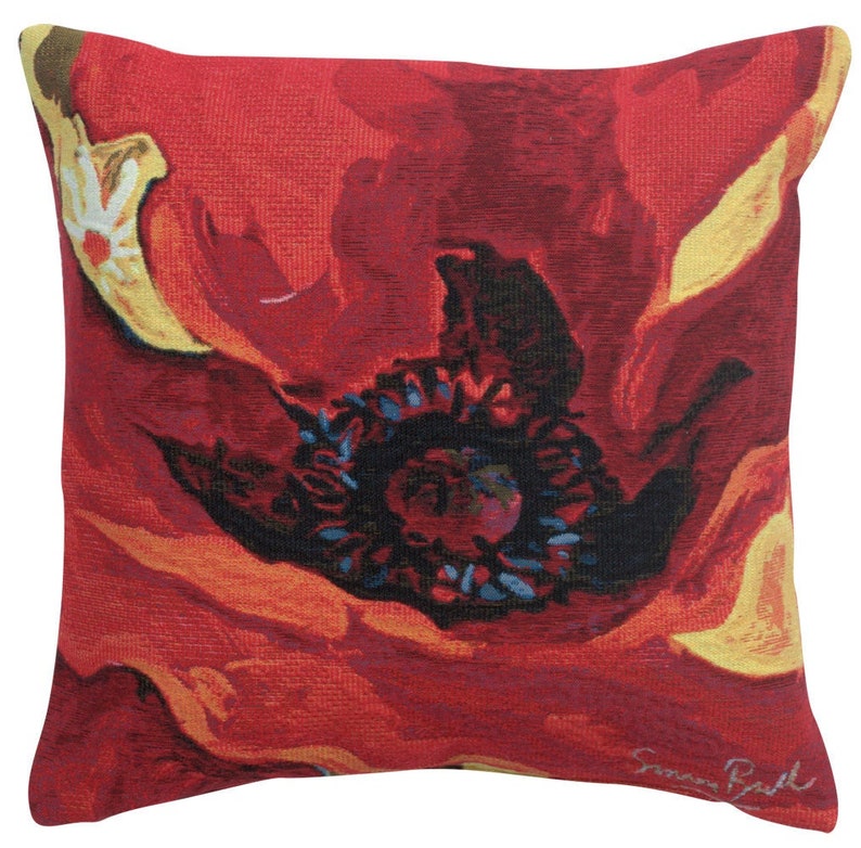 May include: Red poppy flower pillow with a yellow center and a black and blue center. The pillow is made of a textured fabric and has a signature in the bottom right corner.