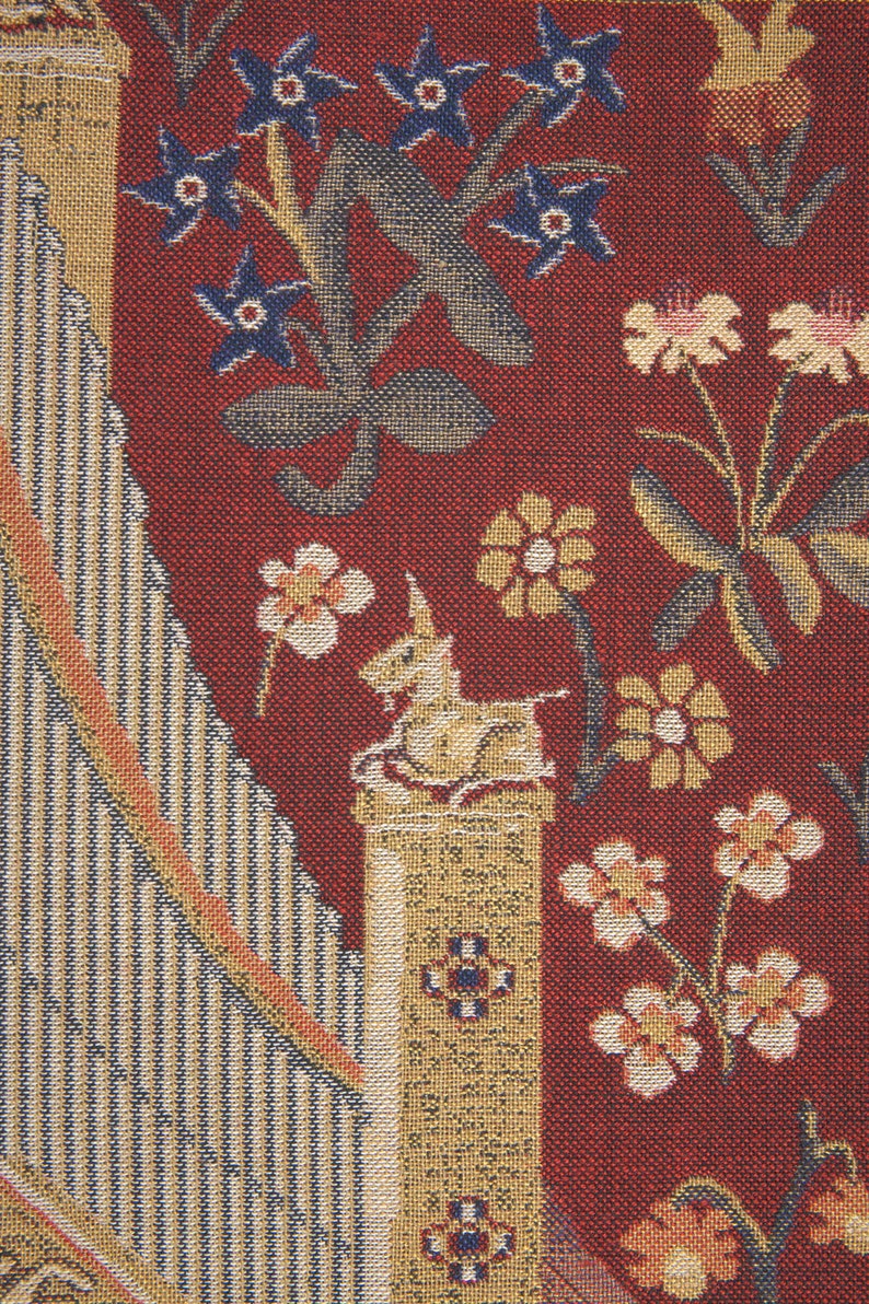 May include: A tapestry with a red background featuring a unicorn on a column, surrounded by floral designs in shades of blue, yellow, and white.
