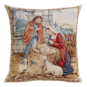 Könnte beinhalten: Ein dekoratives Wandteppichkissen mit einer Weihnachtskrippenszene. Das Bild zeigt Maria, Josef und das Jesuskind in einer Krippe, mit Schafen und einem rustikalen Hintergrund. Das Kissen hat einen beigen Rand mit einem sich wiederholenden Muster.