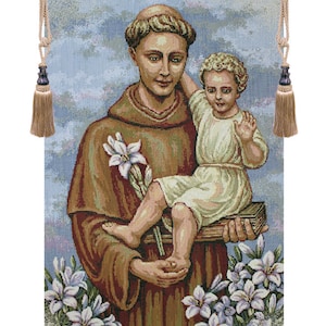 May include: Tapestry depicting a religious figure holding a child, surrounded by white lilies. The figures are dressed in brown robes and white garments. The tapestry is framed by decorative rods and tassels.