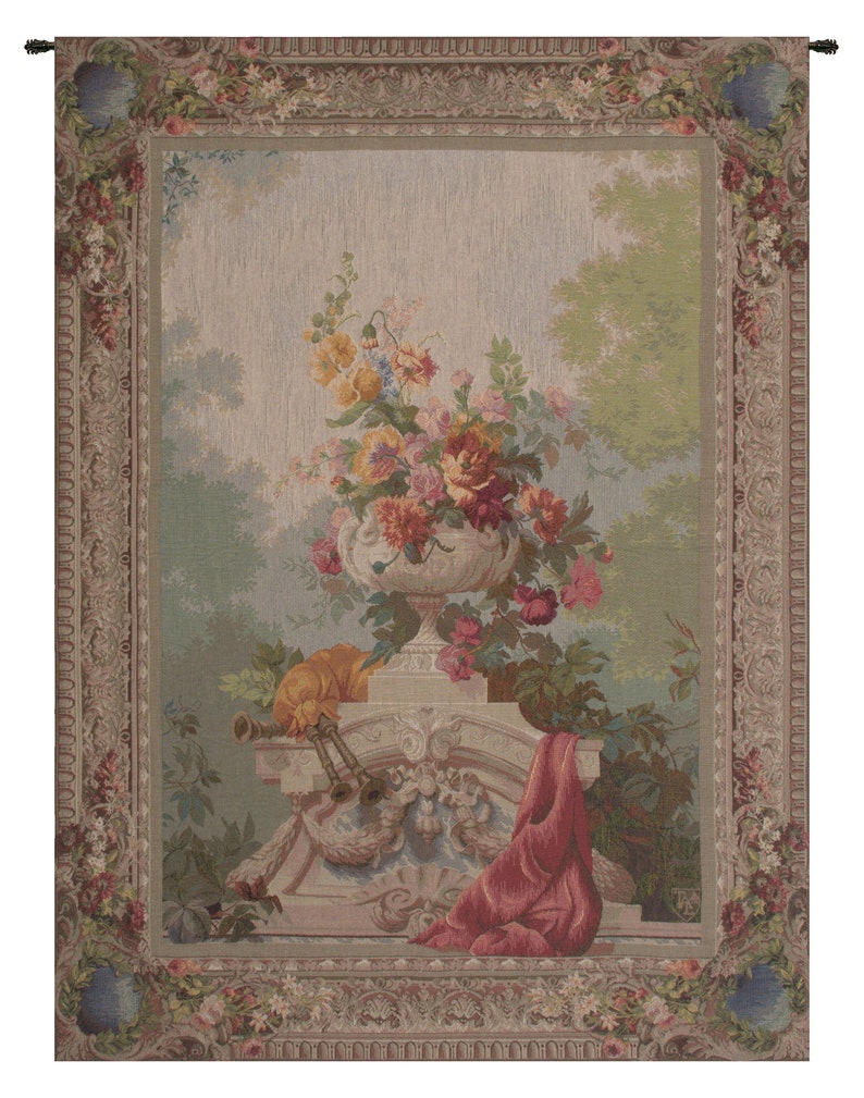 May include: A tapestry with a floral motif. The tapestry features a vase filled with pink, red, yellow, and white flowers. The vase is on a pedestal with a red cloth draped over it. The tapestry has a beige background with a floral border.