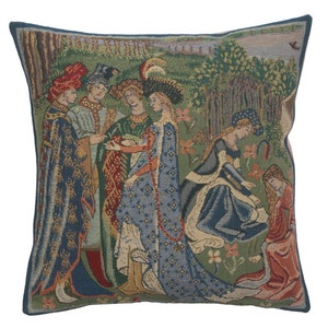 May include: A tapestry pillow featuring a medieval scene with five figures in a garden setting. The figures are dressed in colorful robes and are interacting with each other. The background is a lush green forest with flowers and trees.
