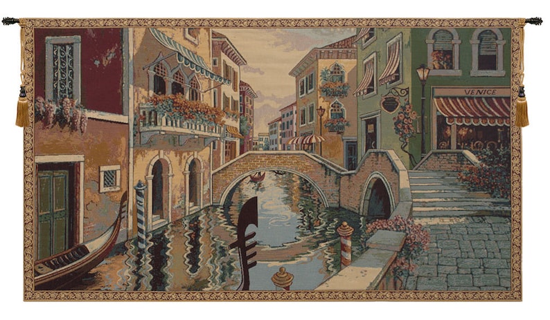 May include: A tapestry depicting a scene in Venice, Italy. The tapestry features a canal with a bridge, buildings on either side of the canal, and a gondola in the water. The buildings are painted in shades of yellow, brown, and green. The canal is a deep blue color, and the gondola is a dark brown color. The tapestry has a gold border with a repeating pattern.