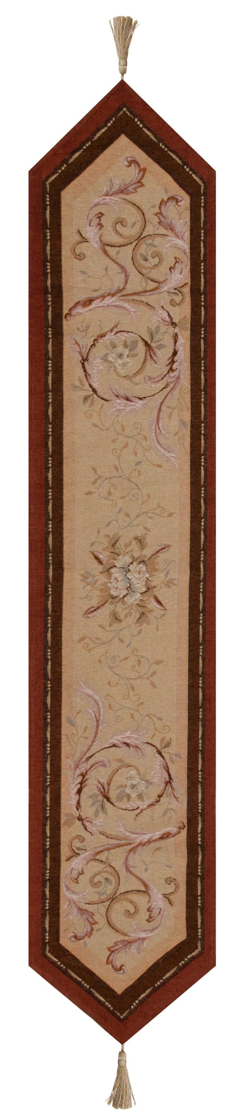 May include: A beige table runner with a brown and red border. The runner has a floral design with pink and white flowers and leaves. The runner has tassels on each end.