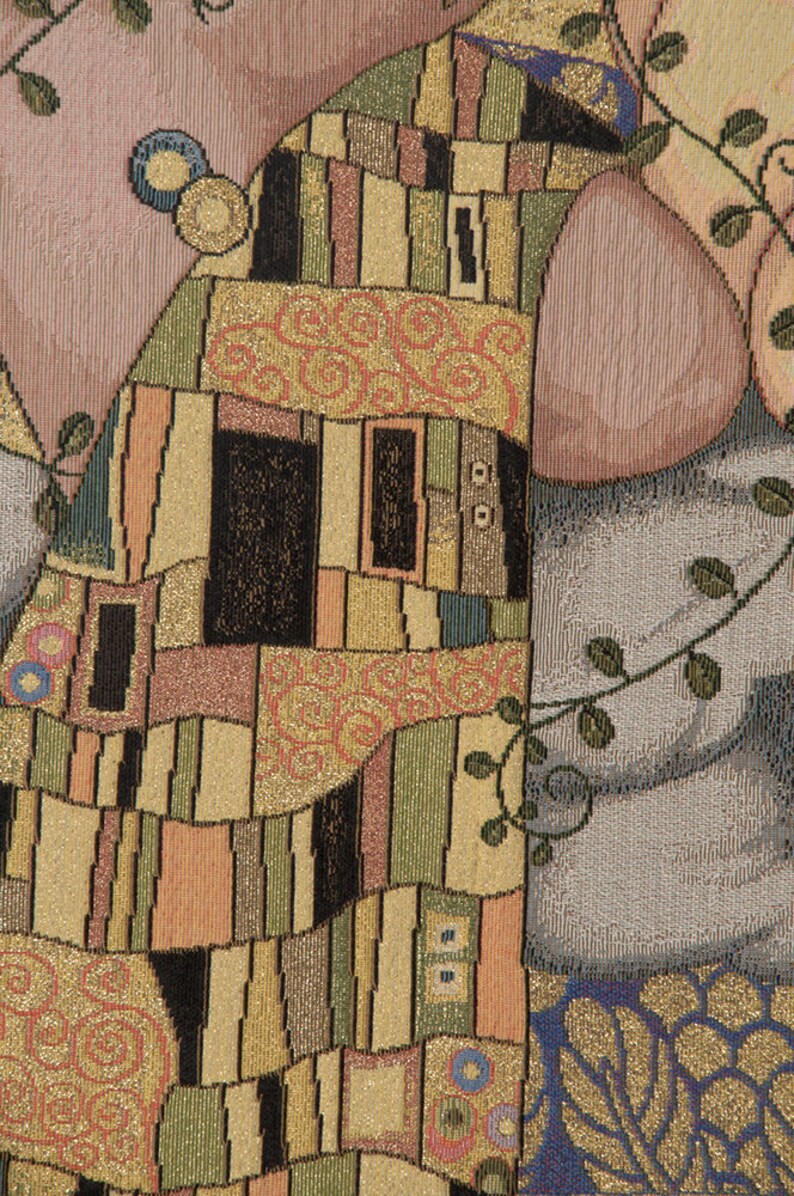 May include: A tapestry featuring a close-up of two figures embracing, with a geometric pattern in gold, black, and brown. The figures are partially obscured by the pattern, creating a sense of mystery and intimacy.