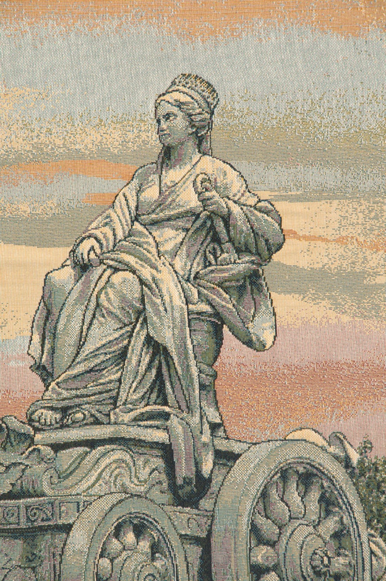May include: A tapestry depicting a woman in a flowing robe, seated on a chariot with large wheels. The tapestry has a muted color palette of beige, brown, and green.