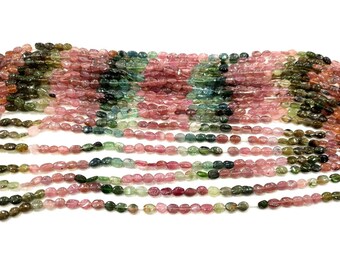 May include: A strand of multi-colored oval-shaped gemstone beads. The beads are a mix of pink, green, and black.