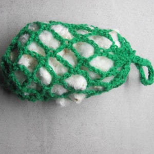 May include: A handmade, green crocheted net filled with white cotton balls. The net has a loop for hanging. The item is likely a reusable cotton ball holder or a decorative item for the home. The crochet work is visible and detailed.