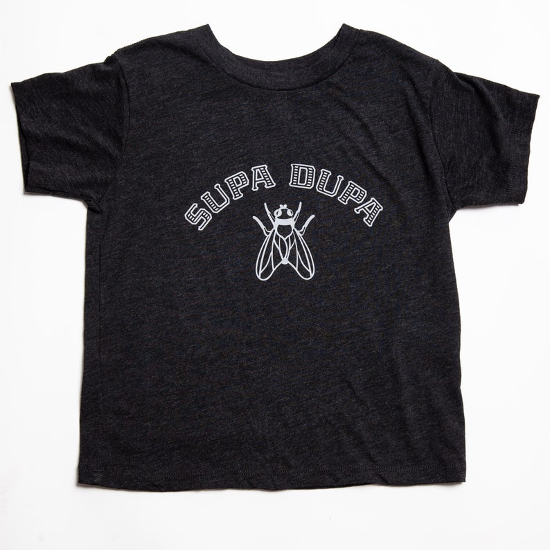May include: A dark gray t-shirt with a white graphic of a fly and the text "SUPA DUPA" in a collegiate font.
