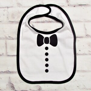 May include: White baby bib with a black bow tie and button design.