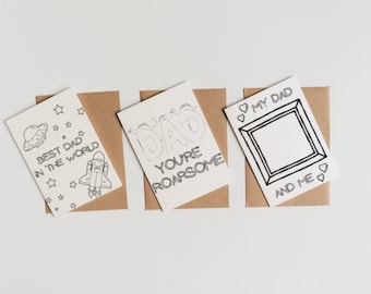 Op de afbeelding: Vier blanco wenskaarten met zwart-wit illustraties en tekst. De kaarten tonen een raket, een UFO, het woord "DAD" met de tekst "You're Roarsome", en een fotolijst met de tekst "My Dad and Me".