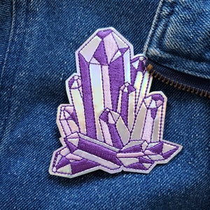 May include: A purple and white iridescent crystal patch with a glittery finish. The patch is embroidered with detailed stitching and is perfect for adding a touch of sparkle to any project.