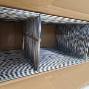May include: A cardboard box filled with a large quantity of silver metal wire frames. The frames are stacked neatly and secured with twine.