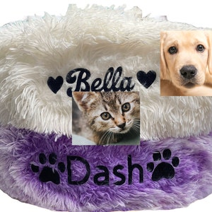 May include: White and purple fluffy pet bed with the names "Bella" and "Dash" embroidered on it. The bed has a heart and paw print design. There are pictures of a cat and a dog on the bed.