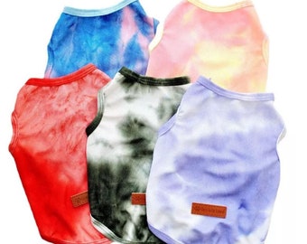 May include: Five sleeveless dog shirts in tie-dye patterns. The shirts are in red, green, blue, pink, and purple.