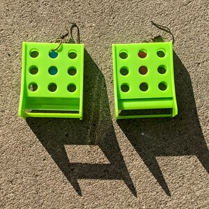 May include: A pair of lime green earrings with a grid of holes. Each earring has a small blue and red circle in the center.