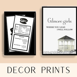 May include: Two black framed prints. The left print is a black and white menu for Luke's Diner with the text "Luke's" and "Drinks & Sides" and "Specials". The right print is white with black text that reads "Gilmore Girls" and "Where you lead I will follow". The print features a white gazebo with a black roof and a bicycle in front of it.