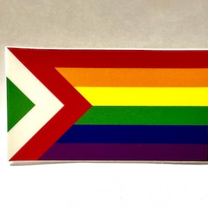 May include: Rectangular sticker featuring a Pride flag design. The flag has horizontal stripes in rainbow colors, with a red, white, and green chevron on the left side. The sticker is on a white background.