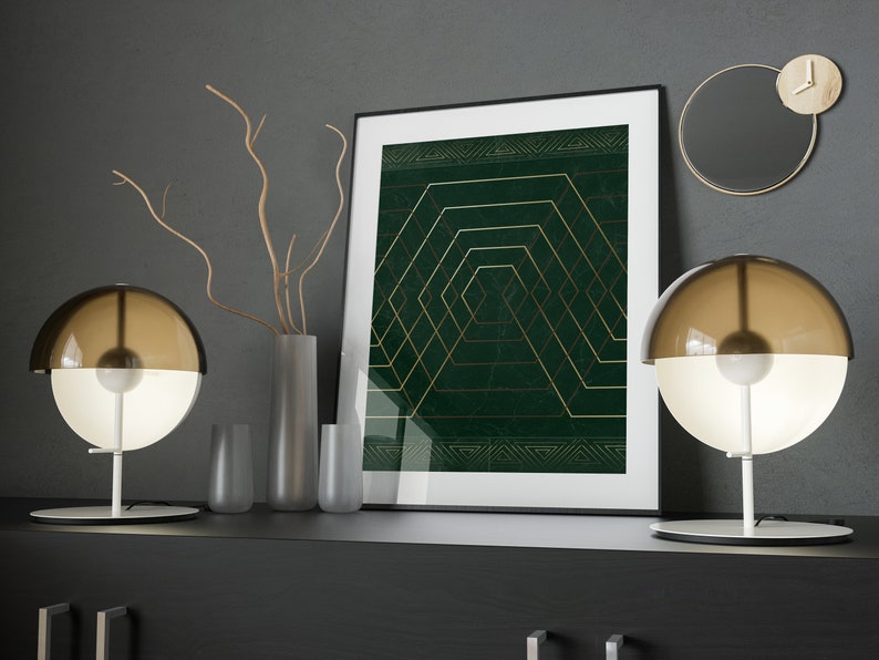 May include: Two modern table lamps with brown glass shades and white bases, a framed print with a green background and gold geometric design, and a vase with dried branches on a black shelf.