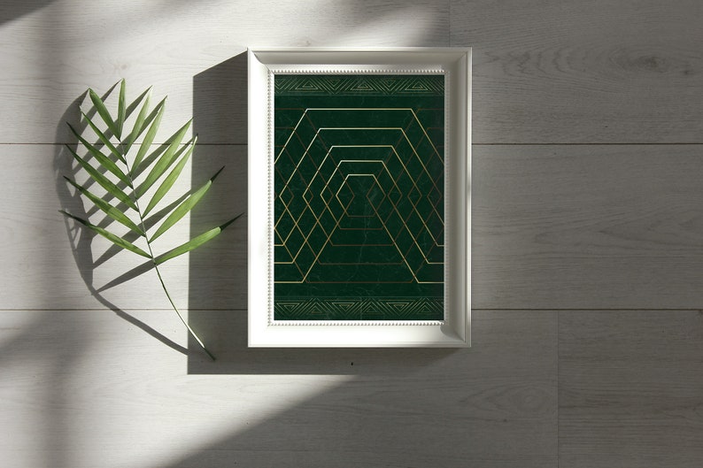 May include: A framed print with a geometric design in gold and green. The design features a series of overlapping squares and hexagons, creating a sense of depth and perspective.